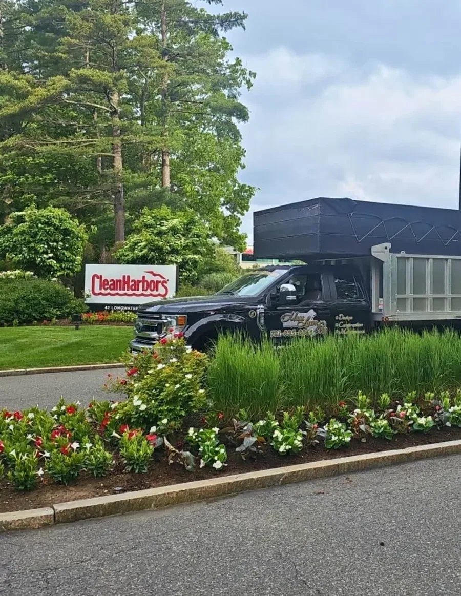 Mass Lawn Pros commercial truck parked beside a landscaped bed at a business property