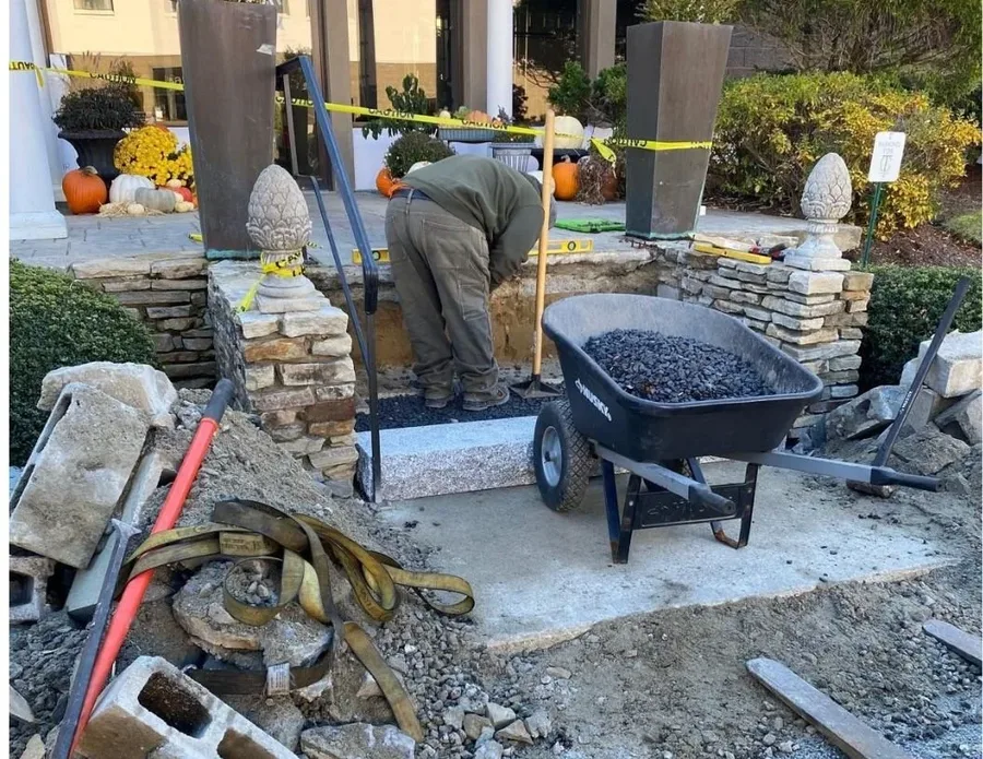 Crew member building a stone entranceway with granite steps