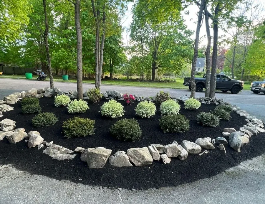Landscaped flower bed with boulder border, mulch, and flowering plants